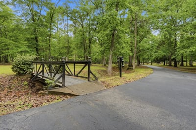 Welcome to a tranquil wooded retreat, featuring a picturesque bridge.