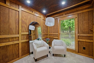 Cozy sitting area features natural wood accents, ample light, and direct views of the lush outdoor setting.