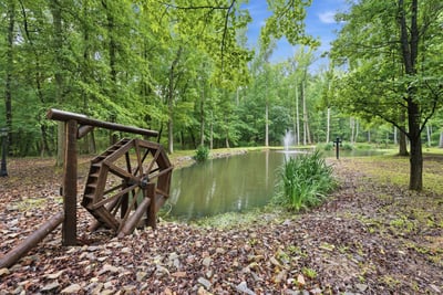 Beautifully landscaped property featuring a tranquil pond and fountain! wheel. Perfect area for outdoor relaxation.