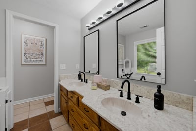 Modern bathroom featuring dual sinks, sleek fixtures, and a spacious layout with ample natural light.