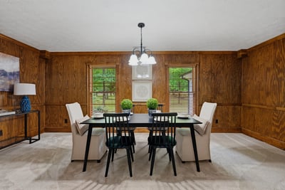 Inviting dining room featuring rich wood paneling and abundant natural light from large windows.
