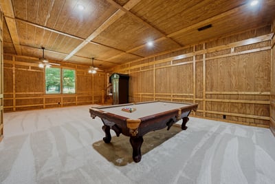 Spacious game room featuring rich wood paneling and recessed lighting
