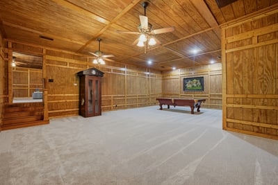 Spacious, wood-paneled entertainment room features ample lighting, and new carpet.