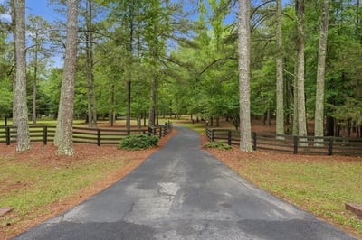Discover a spacious property nestled in a lush, wooded setting with a welcoming private driveway.