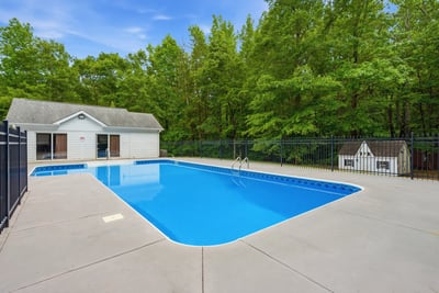 Discover this inviting backyard oasis featuring a spacious pool and a private poolhouse, surrounded by lush greenery.