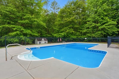 Discover a private oasis featuring a spacious pool surrounded by lush greenery, perfect for outdoor relaxation.