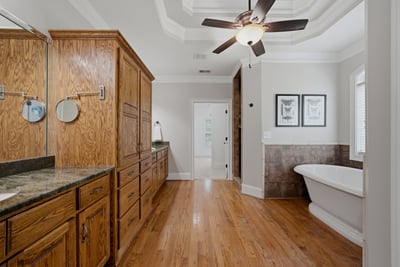 Primary bathroom featuring rich wood cabinetry, modern fixtures, and a freestanding tub for relaxation.