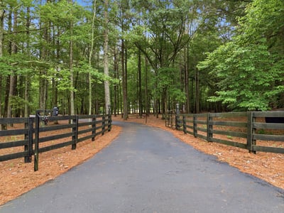 Private, wooded entrance leads to expansive property, offering a tranquil escape surrounded by nature's beauty.