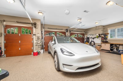 Spacious garage featuring ample storage, three doors, and modern finishes, perfect for vehicle and equipment maintenance. EV charging stations. Most walls are slatwalls. There is ample cabinetry and a closet. The room is both heated and cooled.