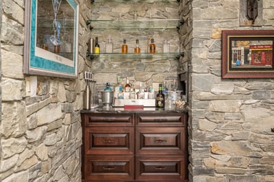 Discover a unique bar area featuring stone walls and custom shelving, perfect for entertaining guests.