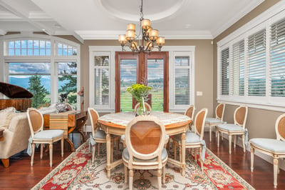 Bright dining room featuring large windows, tray ceilings, intricate details, and a spacious layout ideal for gatherings.