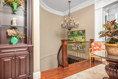 Welcoming foyer with a grand chandelier, showcasing fine craftsmanship and inviting views, drawing you into the living room.