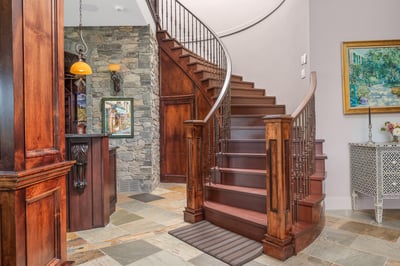 Discover a stunning entryway, as seen from the lower floor, featuring a grand spiral staircase, rich wood accents, and masterful wood craftsmanship.