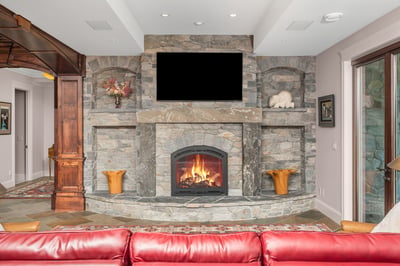 Captivating grand room featuring a massive stone fireplace, entertainment area, perfect for relaxation, gatherings, and sports broadcasting.