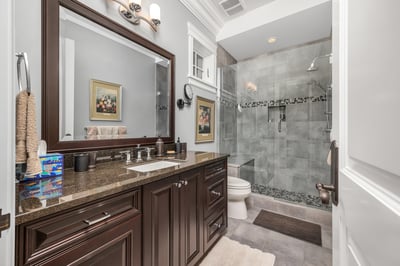 This well-appointed ensuite bathroom features granite countertops, modern fixtures, and a spacious glass-enclosed shower.