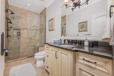 This modern ensuite bathroom features a spacious walk-in shower, granite countertops, and a sophisticated layout.
