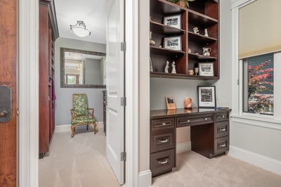 Bright home office in the guest bedroom, featuring custom shelving, natural light, and a cozy seating area for productivity.