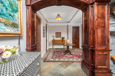 The welcoming transition from the grand room to the bedrooms' entrances and half bathroom features distinctive woodwork and artistic decor.