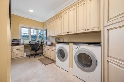 Bright laundry room featuring spacious cabinetry, a dedicated workspace, and large windows for natural light.