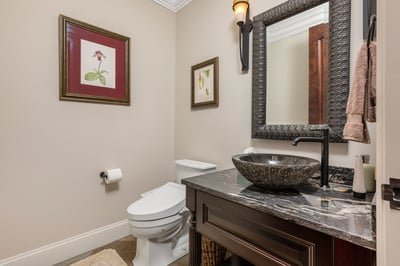 Modern bathroom featuring a unique underlit vessel sink, artistic decor, and a warm, inviting atmosphere.