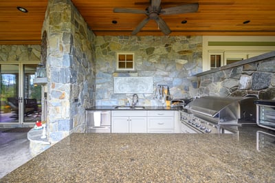 Experience outdoor cooking in this inviting stone-clad kitchen with modern appliances and spacious countertop areas.