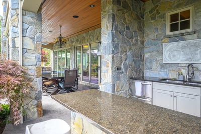 This outdoor space features a spacious stone patio with a built-in bar and comfortable seating.