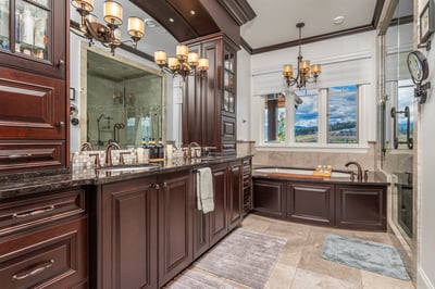 Luxurious bathroom featuring dark wood cabinetry, modern fixtures, and a spacious soaking tub with scenic views.