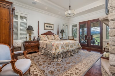 Spacious primary bedroom featuring rich textures, large windows, and a cozy seating area with scenic views.