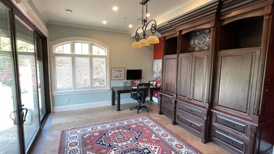 Spacious office featuring custom cabinetry, large windows for natural light, and a decorative area rug.