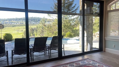 Inviting space features floor-to-ceiling windows showcasing expansive views of lush landscapes and outdoor relaxation areas.