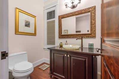 This inviting bathroom features a sleek vanity, distinctive mirror, and warm wood accents throughout.