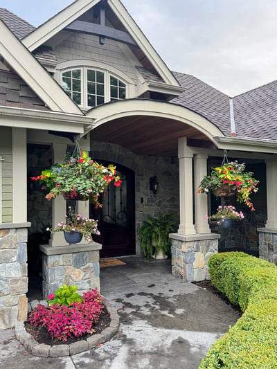 Welcoming entrance with vibrant floral arrangements framed by natural stone, creating an inviting atmosphere.