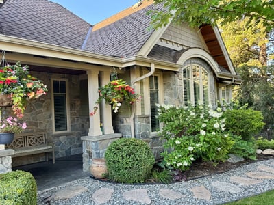 This inviting home features beautiful stonework, lush gardens, and vibrant floral displays, perfect for outdoor enjoyment.