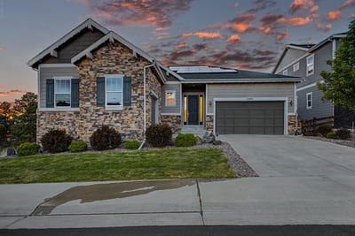 Modern home with stone accents, solar panels, and a spacious lawn, ideal for comfortable living.