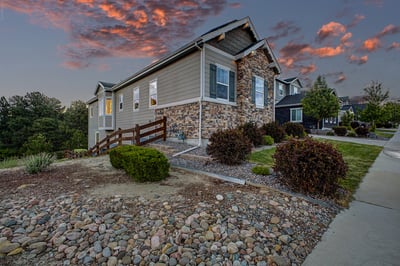 Contemporary hillside home featuring unique stone accents and landscaped grounds with scenic sunset views.
