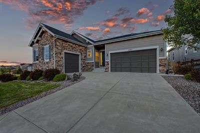 Modern home featuring stone accents, spacious driveway, and beautiful sunset views in a desirable neighborhood.