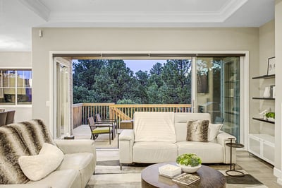 Bright, open living area seamlessly connects to a spacious deck, showcasing stunning views of the surrounding forest.