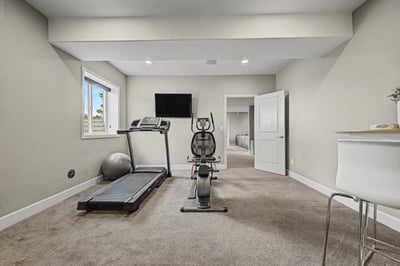 Furnished fitness room with exercise equipment and ample natural light, perfect for an active lifestyle.
