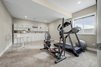 Spacious fitness room featuring modern equipment and ample natural light, ideal for workouts or relaxation.