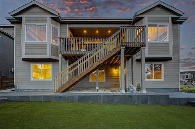 Modern two-story home featuring abundant windows, a spacious deck, and a well-maintained lawn in a desirable neighborhood.