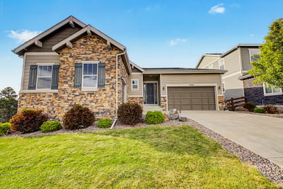 Modern home featuring a stone facade, spacious lawn, and convenient garage in a desirable neighborhood.