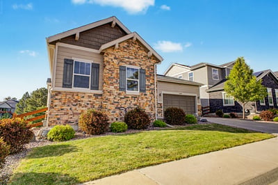 Beautifully designed home with unique stone facade, well-maintained landscaping, and a convenient garage.