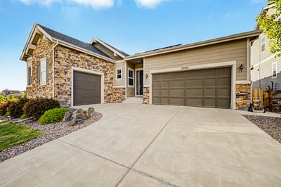 This modern home features a striking stone facade, spacious driveway, and an inviting entryway.