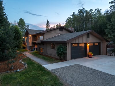 Spacious multi-level home nestled among trees, featuring a large driveway and scenic surroundings.