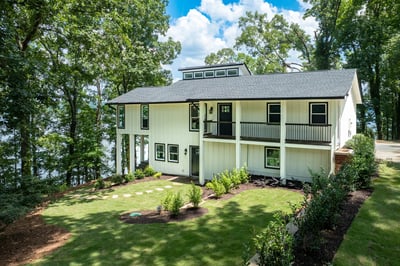 Modern waterfront home surrounded by lush greenery, offering stunning views and direct lake access for outdoor enthusiasts.