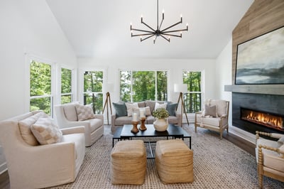 Bright and inviting living room featuring large windows, modern lighting, and a cozy fireplace for warmth.