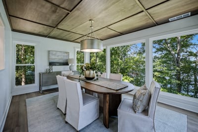 Bright and airy dining area with large windows offering stunning views of surrounding greenery and nature.