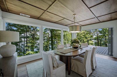 Bright dining area with panoramic windows, offering stunning views of the surrounding nature and outdoor deck.