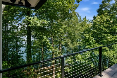 Discover a private balcony overlooking lush trees and tranquil water, perfect for nature lovers.