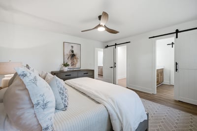 Bright and airy bedroom featuring modern finishes, a ceiling fan, and rustic barn doors.